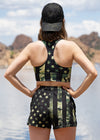 woman looking at a lake in arizona wearing a camo flag stars and stripes sports bra and athletic shorts and a black camo hat