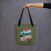 River to Ridge Brand Tote Bag in olive with the Offroad Classic Logo. Featuring a vintage Bronco truck with big tires on a rock with a kayak on top - Woman holding the bag out with her arm