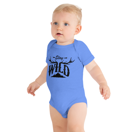 little boy in a blue onesie one piece in blue with the stay wild antler logo on it