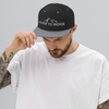 Man with tattoos wearing a River to Ridge Brand flat bill snap back hat in silver and black