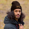 man with long dark hair in a windbreaker wearing a brown WILD beanie with antlers on it