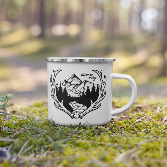 river to ridge logo with mountains and elk antler sheds and a river on white enamel coffee cup sitting in the moss