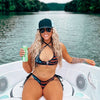 Western Fashion Influencer Kayla Nobble wearing a bikini from River to Ridge Brand that is patriotic and has stars and guns on it, sitting in the front of the boat at the lake