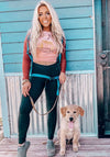 pretty blonde woman with a puppy wearing leggings and a crop top in blush with a tent and sedona arizona mountains and a tent . Kayla Noble for River to Ridge Brand