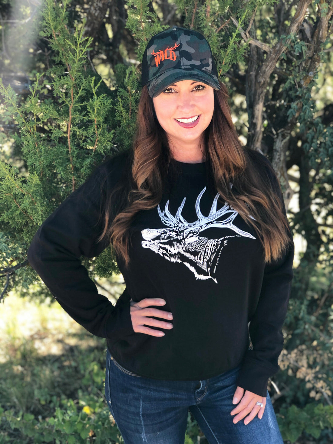  Woman in Elk Sweatshirt in Black in Woods with WILD Camo Hat on 