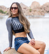 Athletic Woman in Patriotic Grey and Black Flag Crop Top at Lake in Arizona in jean shorts for River to ridge brand