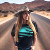 Woman on an open road in the desert wearing a cowboy hat and long red hair and wearing a teal gun flag 2A t shirt in black