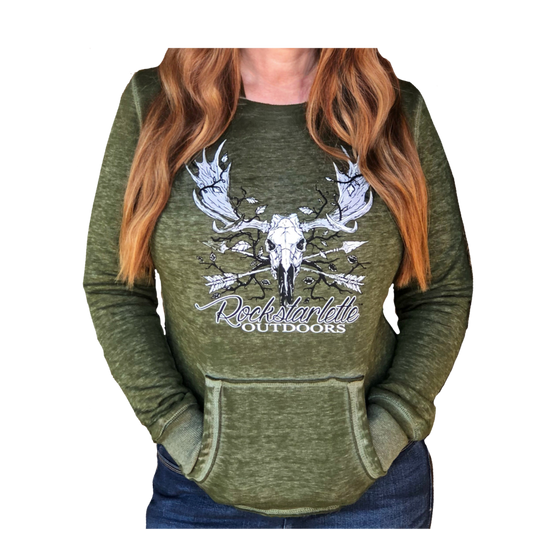 Vintage Wash Olive Hoodie on a woman with red hair and jeans featuring a moose skull with antlers and arrows and rockstarlette Outdoors
