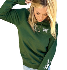  WILD Pullover in green on woman with blonde hair looking down. Logo has elk antlers on the word WILD from the brand River to Ridge