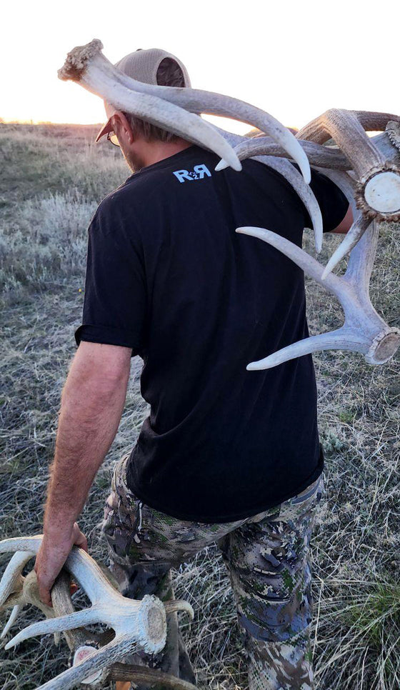 Man carrying elk antler sheds, photo from the back and hes wearing a R2R log t shirt for River to Ridge Clothing Brand