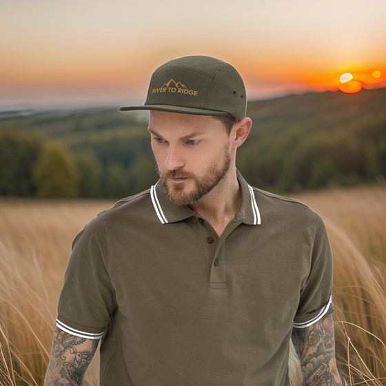 Man outdoors with full sleeve tattoos on both arms, wearing a retro vintage classic Camp Hat in Olive from River to Ridge Clothing Brand