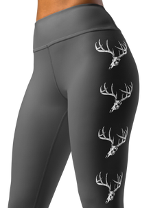  close up photo of a woman wearing grey yoga leggings with a big whitetail buck on them with the euro skull and antlers in grey