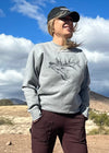 pretty woman standing on dirt road wearing elk sweatshirt, hat and work pants 