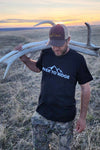 Man Shed hunting for elk antlers carrying them in a River to Ridge Logo Shirt and camo pants
