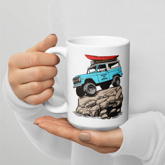 River to Ridge brand coffee mug. Featuring a bronco on top of a rock in vintage blue and the truck has a red kayak on top of it