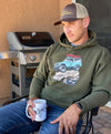 Close up of a guy wearing a River To Ridge Brand hoodie with a vintage classic Bronco on it rock crawling offroad with a red kayak tied on top of it - man is drinking coffee from an elk antler coffee mug