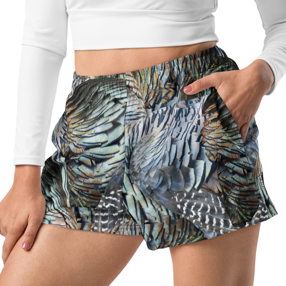 close up of woman wearing relaxed fit athletic shorts with pockets in a turkey feather pattern from river to ridge and a white crop top shirt