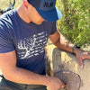 Guy pulling an arrow out of a 3D target wearing a Blue R2R Logo hat and a blue whitetail flag T shirt from River to Ridge Clothing Brand