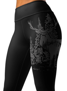  close up of a woman wearing leggings with a wide waistband and a logo of an elk red stag on it in black and grey
