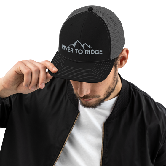 man wearing a River to Ridge Logo black and grey snapback trucker hat