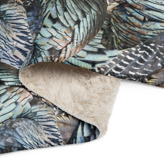 Close up photo of a turkey feather pattern blanket with sherpa fleece on the back side