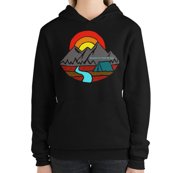 Woman wearing a hoodie in black by a brick wall and it says mountain air feeds my soul with a mountain a river and a tent on it from River to Ridge Brand