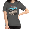 Woman wearing a River to Ridge Brand t shirt in grey with the offroad classic logo of a bronco rock crawiling with big tires and a kayak on top