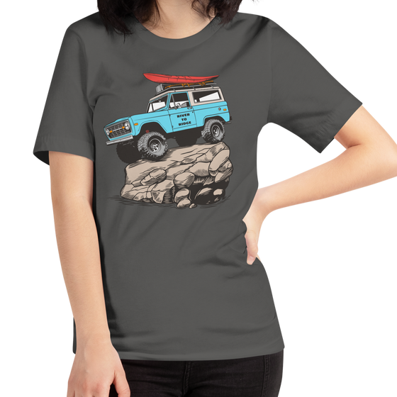 Woman wearing a River to Ridge Brand t shirt in grey with the offroad classic logo of a bronco rock crawiling with big tires and a kayak on top