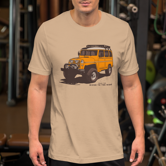 Mens T shirt in tan with a drawing of a landcruiser offroading truck in yellow with big tires from the brand River to Ridge - on a guy at the gym