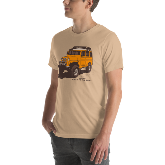 Mens T shirt in tan with a drawing of a landcruiser offroading truck in yellow with big tires from the brand River to Ridge - on a young man in jeans