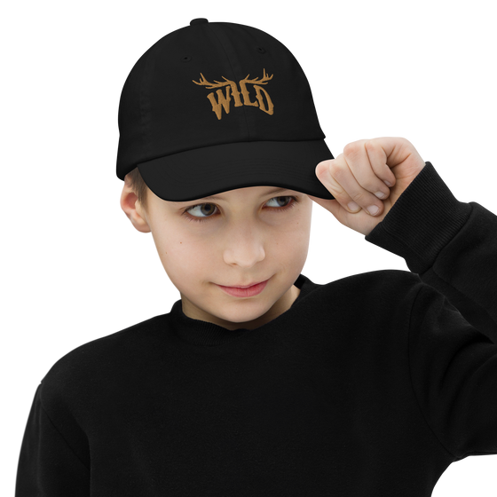 Kids WILD Logo hat from River to Ridge Brand. featuring the Stay Wild logo in gold stitching with elk antlers on the I and L. Photo of a little boy wearing black shirt and wearing the hat
