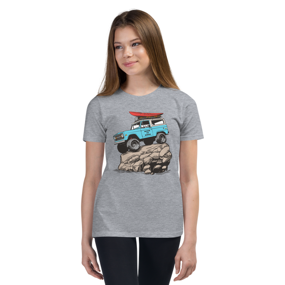 Offroad classic logo T shirt for kids from River to Ridge Brand. Features a Bronco up on a rock with big tires on it and a red kayak on top, vintage truck T. Photo of young girl pre teen wearing the shirt