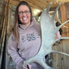 Person holding a large deer antler indoors with wooden walls.