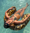 Woman in pool wearing a camo bikini with turquoise straps from River to Ridge clothing brand