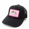 A black trucker hat with a pink and white 'FAITH' mountain patch on the front, resting on a stone wall outdoors.