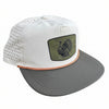 White and gray cap with a green patch featuring a turkey design on a stone surface.
