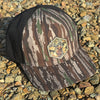Camouflage baseball cap with a logo on a gravel surface