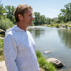 Man wearing a white long-sleeve shirt outdoors with trees and grass in the background