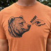 A close-up of a person wearing a heathered orange crewneck t-shirt with a black graphic of a bear's head and a pointing hand with the word 'BOOP!' printed on the chest, set against an outdoor background.