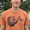 A man wearing a heathered orange crewneck t-shirt with a graphic of a brown bear and a pointing hand saying 'BOOP!'.