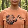 A close-up of a person wearing a heathered orange crewneck t-shirt with a black graphic of a bear's head and a pointing hand saying 'BOOP!'.