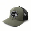 An olive green trucker cap with a black mesh back, resting on a stone pillar outdoors. The front features a black arrowhead patch embroidered with the text 'GENESIS 27:3' in white.