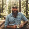 Camouflage cap with a graphic of a cowboy riding an alligator on a white background
