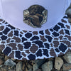 Cap with duck camo print brim and white top, featuring a dog emblem on a rocky surface.