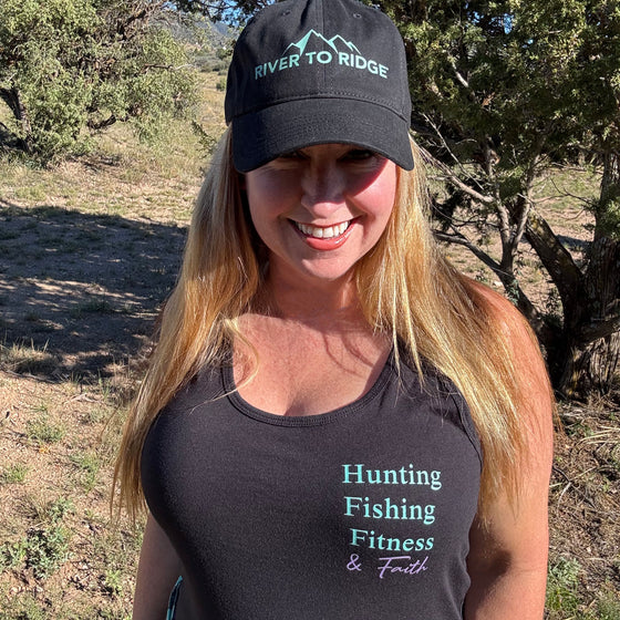Woman wearing a black cap and tank top with text in an outdoor setting