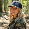 Person wearing a cap with 'Jesus SAVES' text in a forest setting