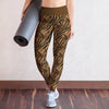 Woman in athletic wear holding a yoga mat against a plain wall.
