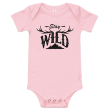  Stay Wild Logo on a baby one piece in pink and the logo has elk antlers on it and a mountain, onesie