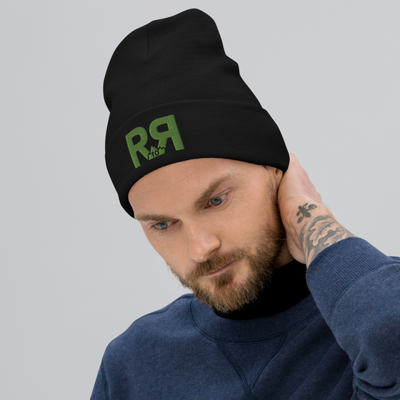 Product mockup of a River to Ridge Logo Beanie in black with green stitching R to R worn by a man with a beard