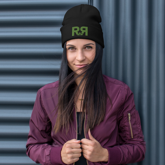 Product mockup of a River to Ridge Logo Beanie in black with green stitching R to R worn by a woman with long hair and a purple jacket